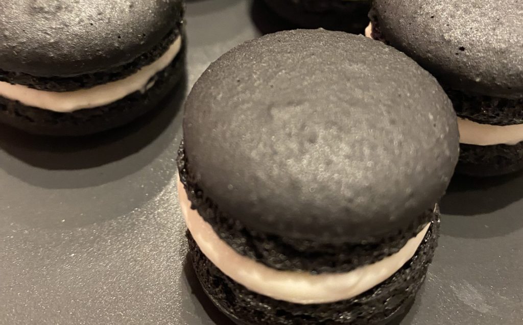 Macaron noir au charbon actif, garni d’une ganache montée à la vanille, atelier pâtisserie Boom Cake à Rumilly, Annecy et Aix-les-Bains