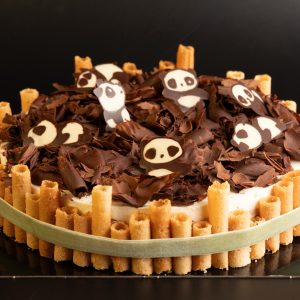 Vue d’ensemble du gâteau 3 chocolats décoré de pandas en chocolat, copeaux de chocolat noir et bambous en biscuits cigarettes, réalisé par Boom Cake à Rumilly